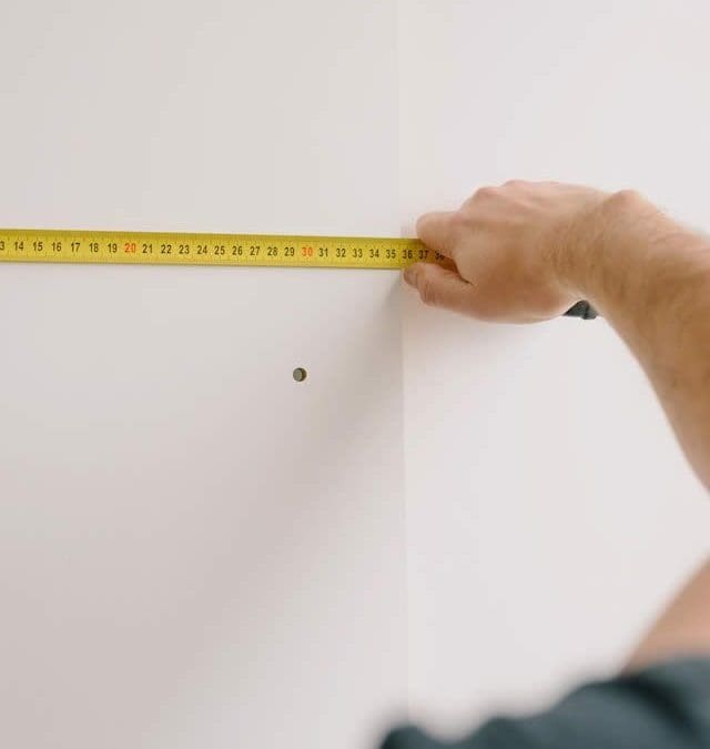 Builder measuring a wall with a tape measure to ensure drywall precision