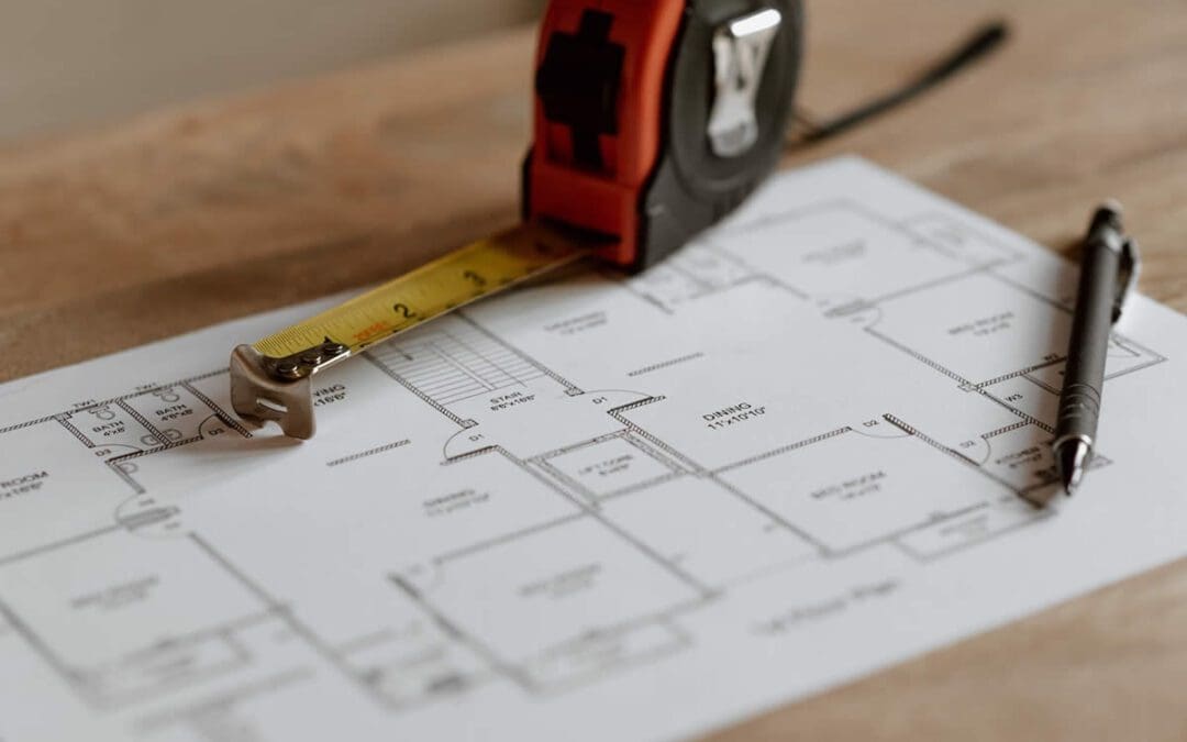 Tape measure and measured drawings on a wooden table to ensure efficiency in drywall construction