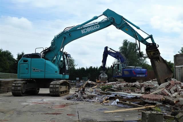 digger adding more rubbish to pile of construction waste